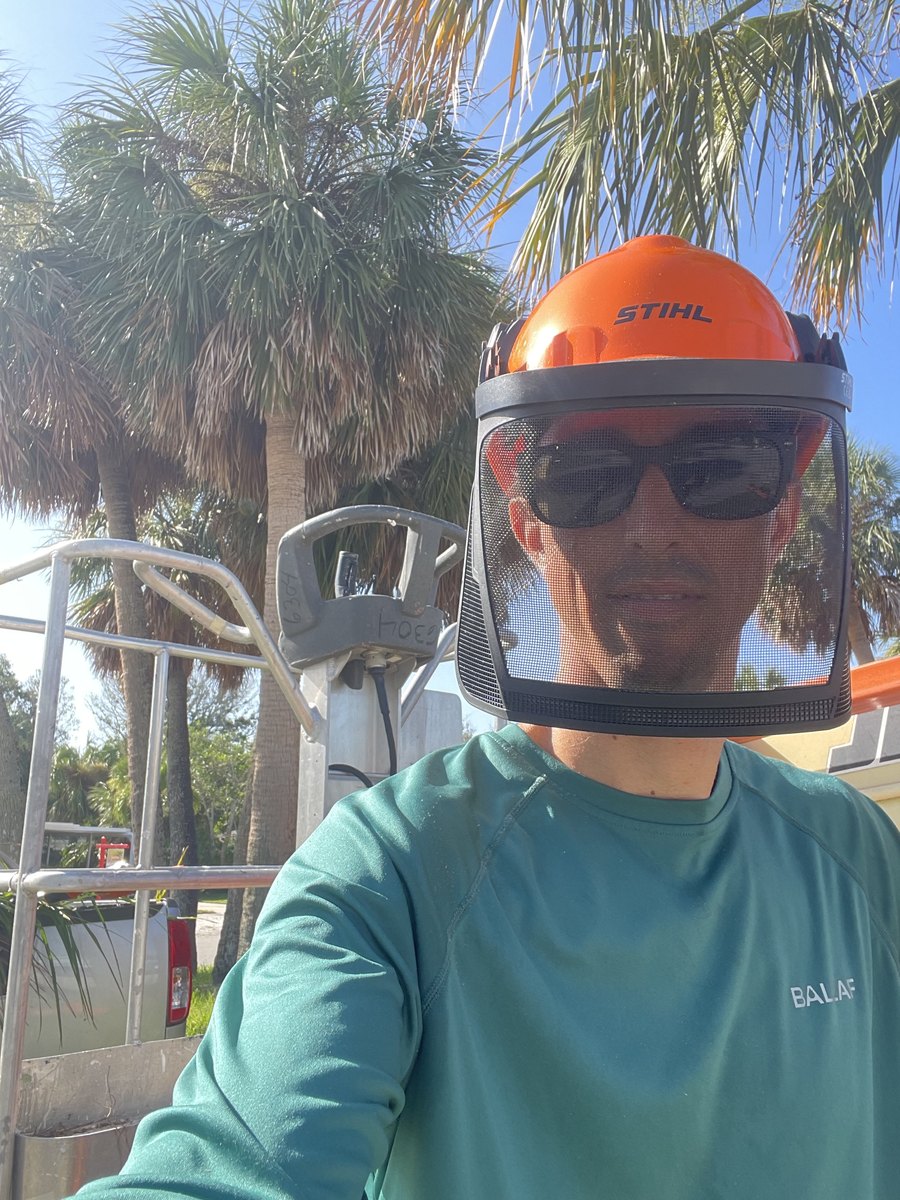 TLC owner Tyler Greeley wearing helmet, face protection and safety glasses beside landscaping equipment